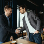 two-businessmen-shaking-hands-while-meeting-lobby