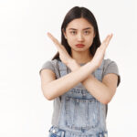 waist-up-serious-looking-confident-determined-asian-brunette-woman-demanding-stop-show-cross-arms-frowning-sulking-warn-give-strong-refusal-decline-hideous-offer-prohibiting-taboo-white-wall