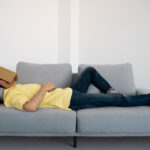 full-shot-man-laying-couch-with-book