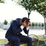 sad-businessman-sits-bank-outside-street