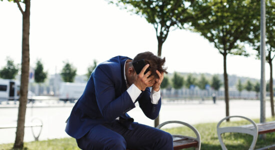 sad-businessman-sits-bank-outside-street